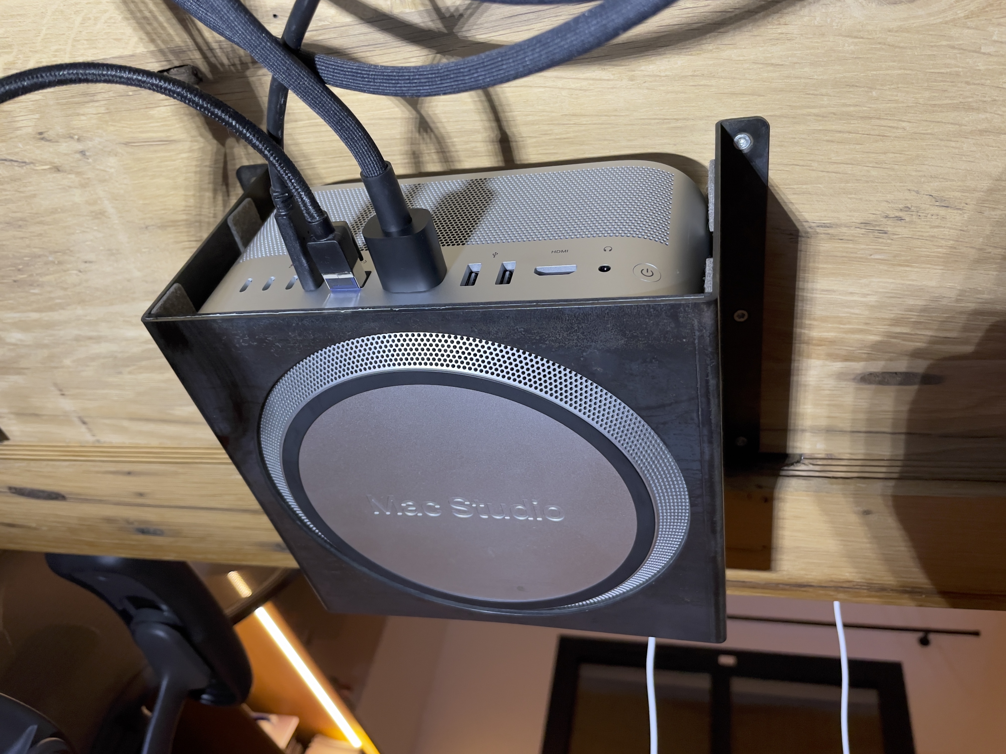 Photo montrant le support de fixation fixer sous le bureau avec le Mac Studio installer vue de l’arrière et ces câbles
